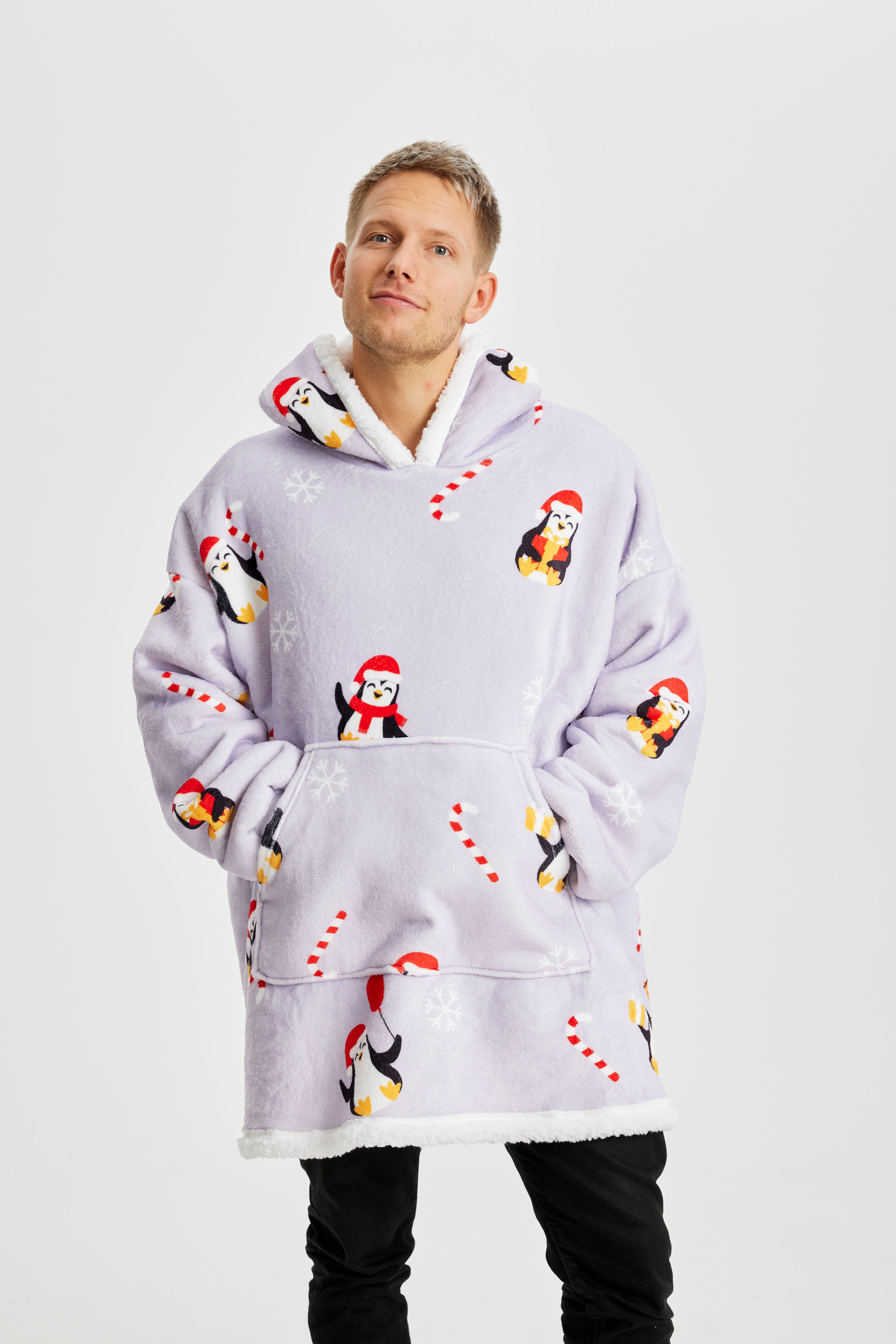 En mand med hænderne i hans julehoodie med pingviner.